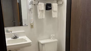 Ein Badezimmer mit Waschbecken, Spiegel, Handtuchhalter, Toilette und Mülleimer.