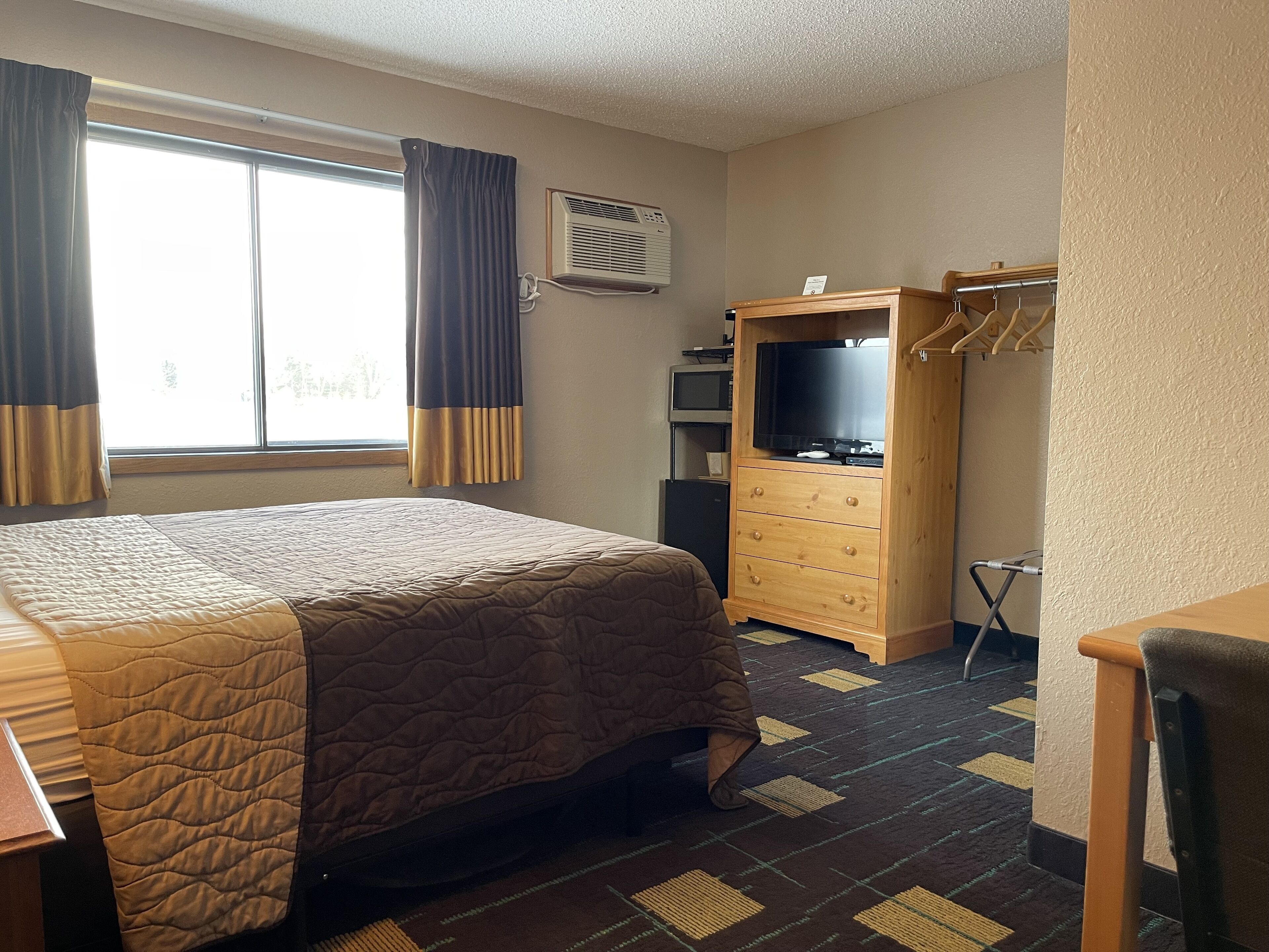 Une chambre d’hôtel équipée d’un lit, d’une télévision, d’une armoire et d’un bureau.