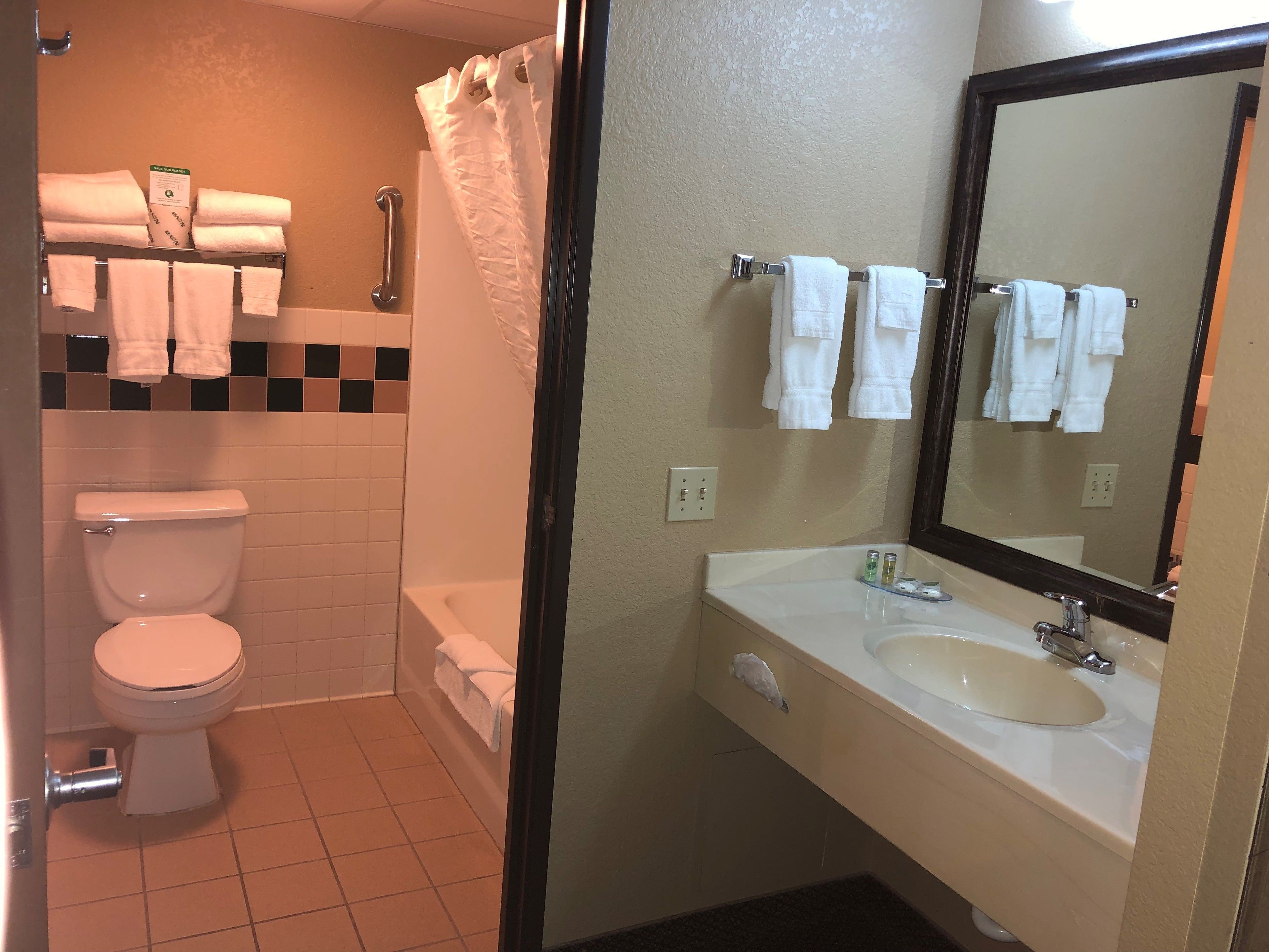 Een badkamer met toilet, douche, wastafel en spiegel.