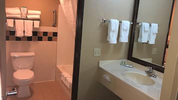 Une salle de bain équipée de toilettes, d’une douche, d’un lavabo et d’un miroir.