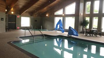 Swim and unwind in our pool area, featuring a spacious pool, pool ladders, and a seating area with a table and chairs.