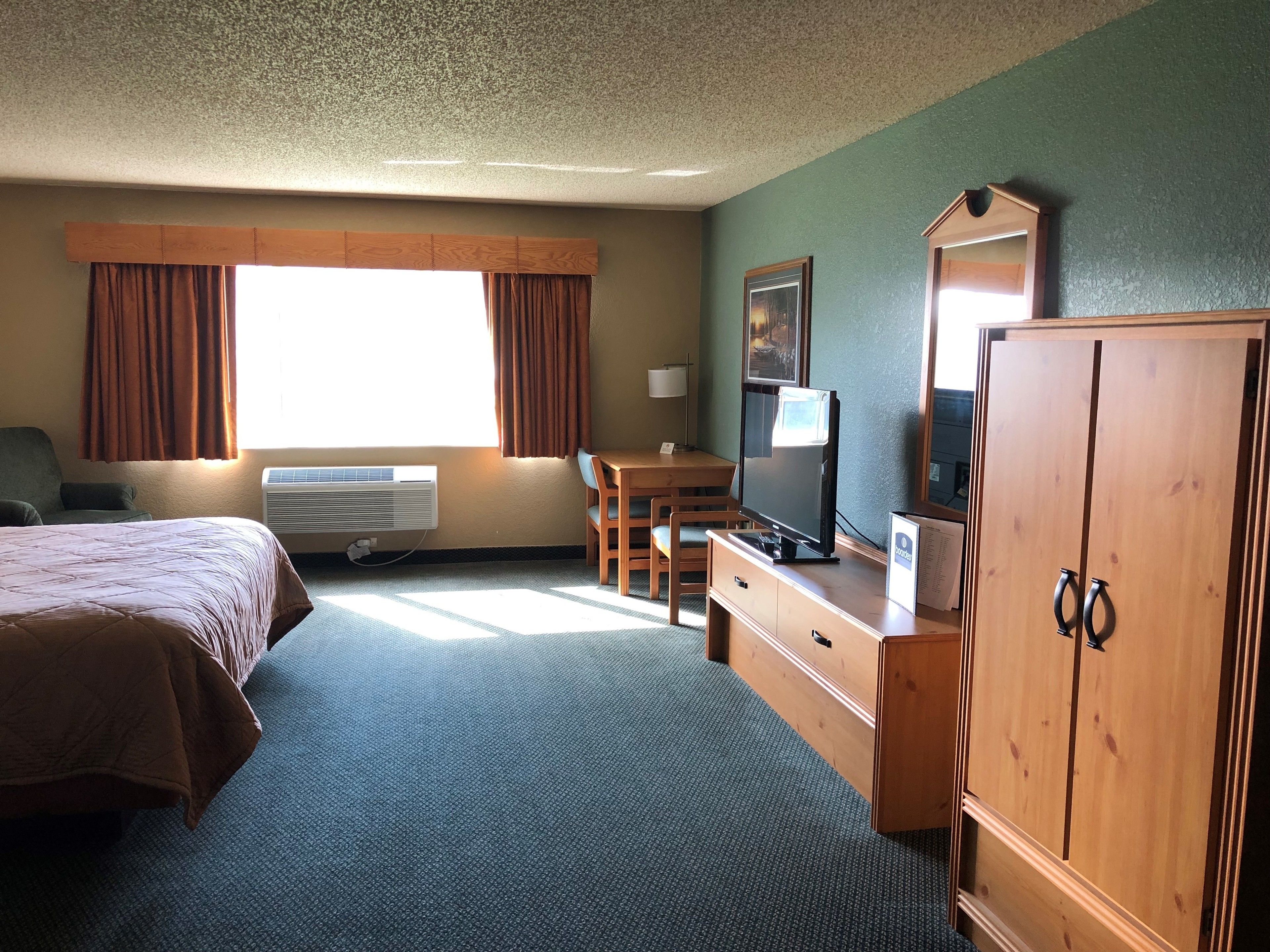 A hotel room with a bed, a desk, a TV, and a wardrobe.
