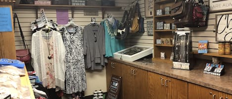 A small boutique with racks of clothing, a display of handbags, and a sign about retirement.