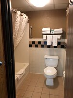 Un baño con inodoro, ducha con cortina y toallero con toallas.