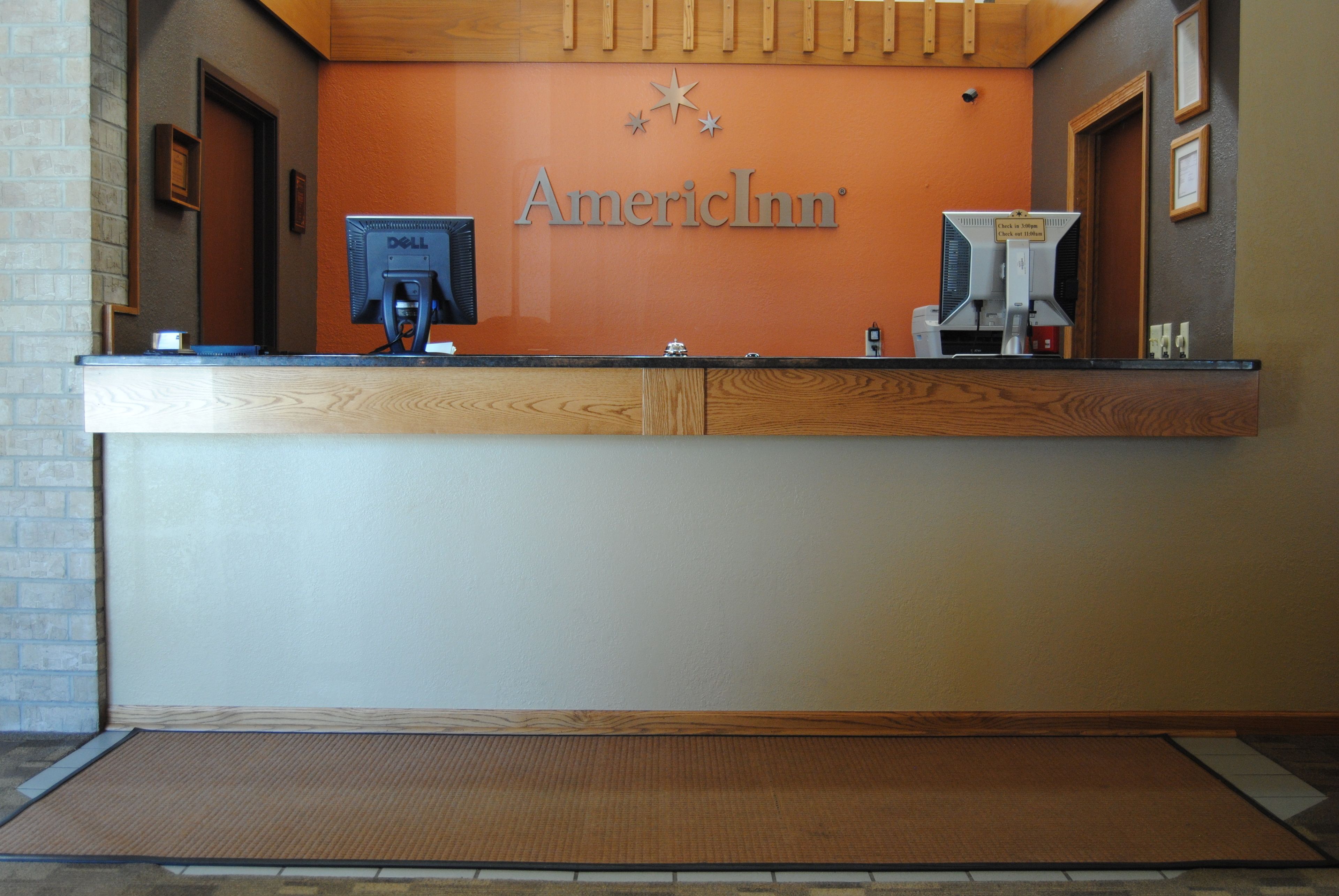 Una recepción con un letrero de American Inn, una computadora Dell y una máquina de café.
