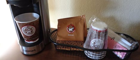 A coffee maker, a paper cup, a reusable coffee cup, a reusable mug, and a reusable water bottle on a table.
