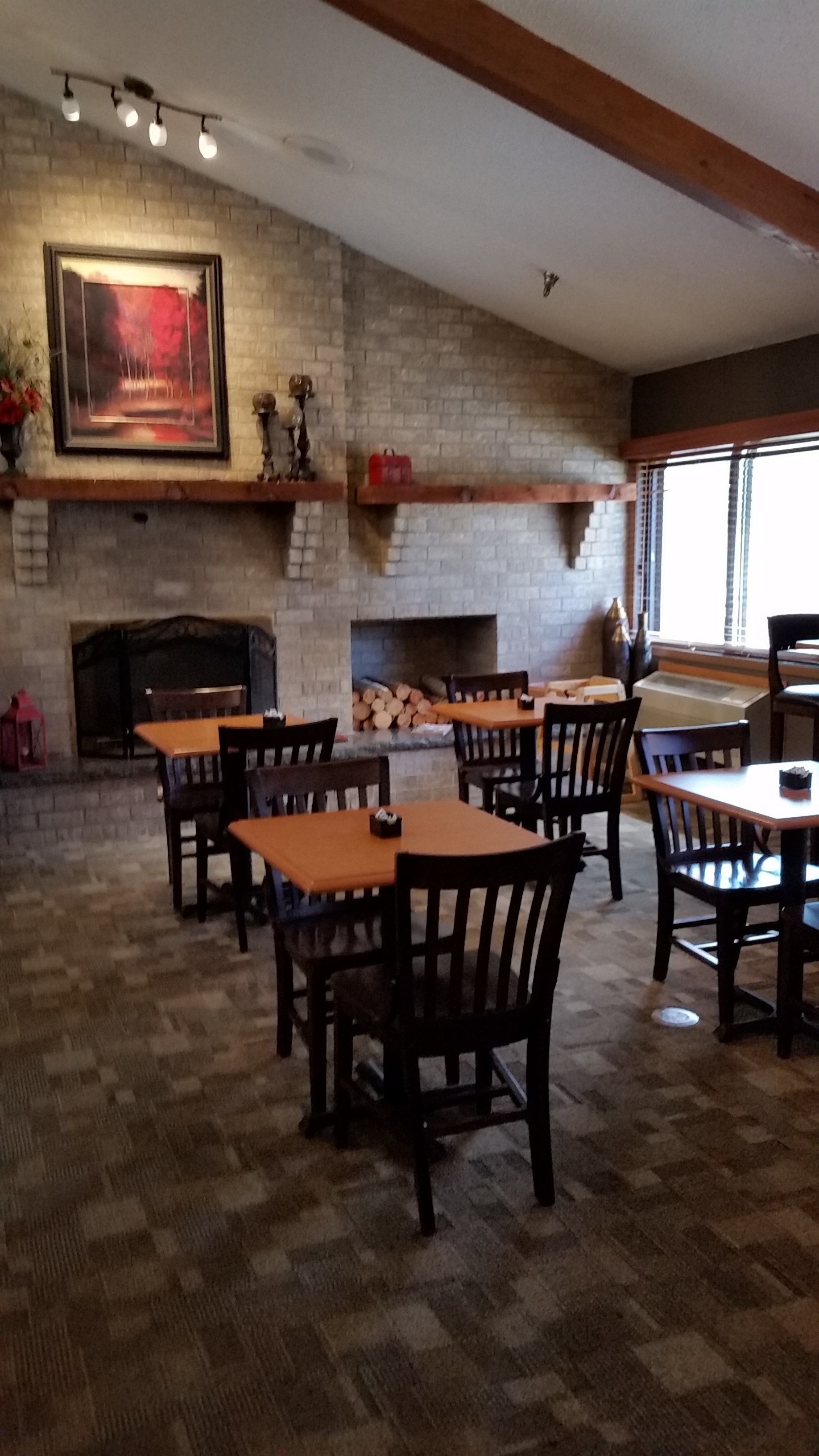 Un restaurant aux murs de briques, doté d’une cheminée et de tables et chaises en bois.