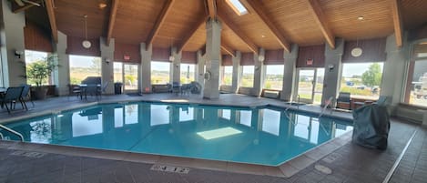 Une piscine intérieure dotée d’un plafond en bois et de grandes fenêtres.