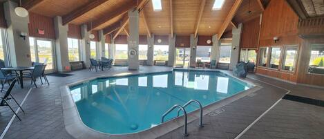 An indoor swimming pool with a wooden ceiling and large windows.
