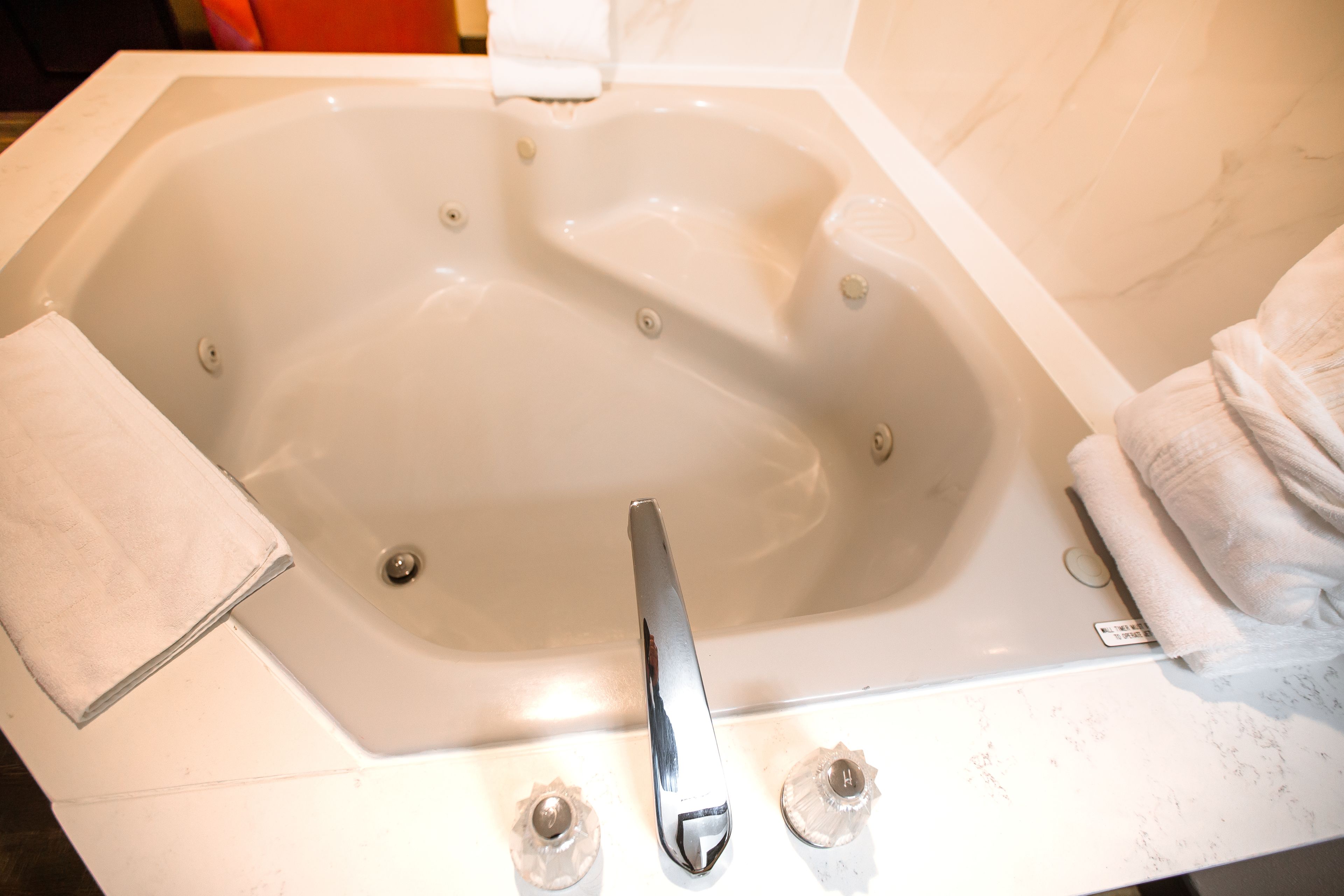 A large, white bathtub with a chrome faucet and control knobs.