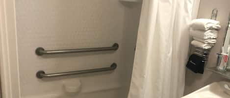 A bathroom with a shower, a sink, and a towel rack.