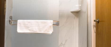 A modern bathroom with a glass shower enclosure, a white toilet, and a wooden door.