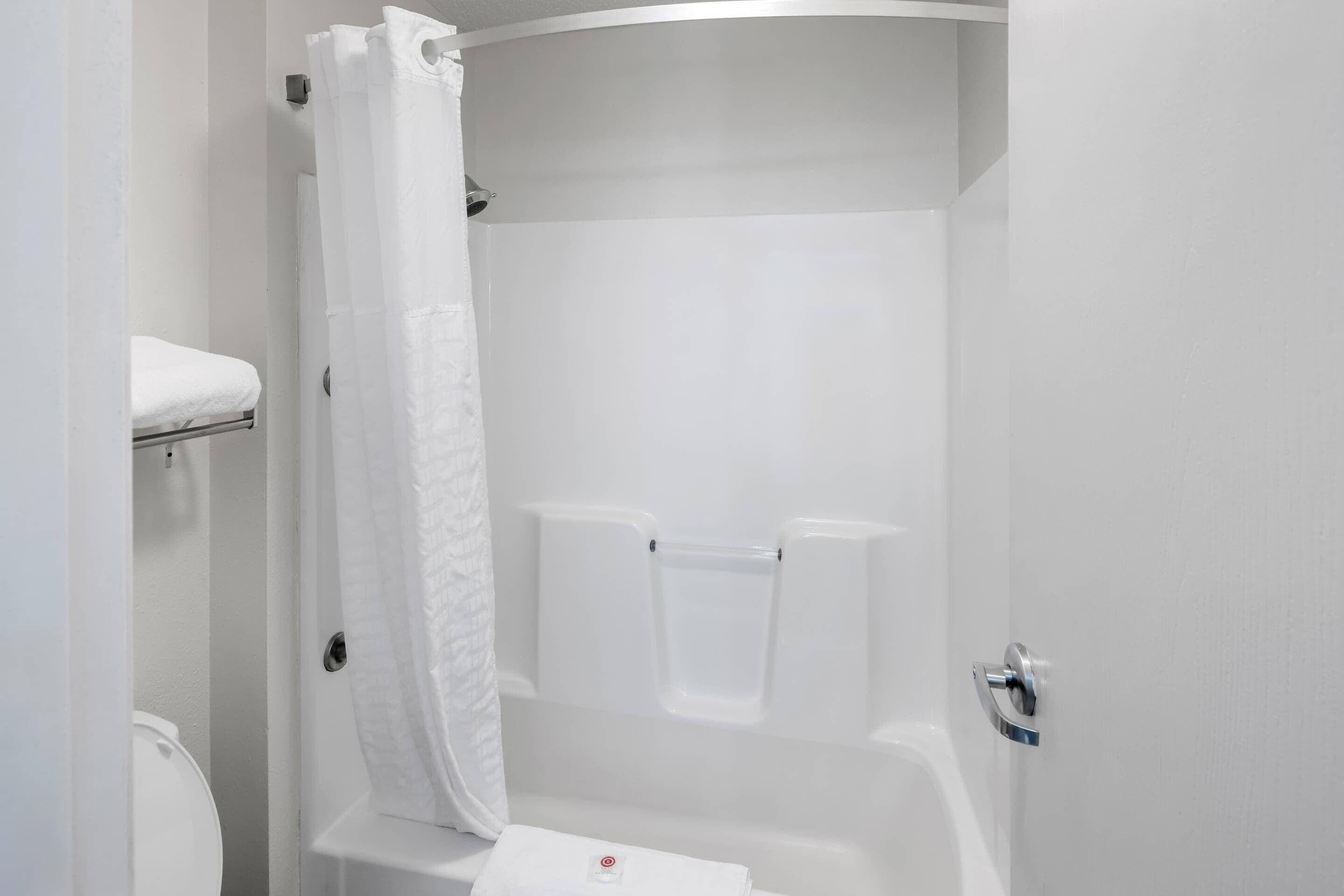 Een witte badkamer met douchegordijn, handdoekhouder en toilet.