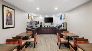 A hotel dining area with tables and chairs, a kitchen counter, and a flat-screen TV mounted on the wall. - Comfort Inn Mount Vernon Downtown (Mount Vernon)