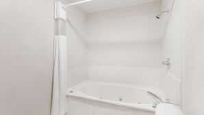 Un baño blanco con bañera, ducha e inodoro.