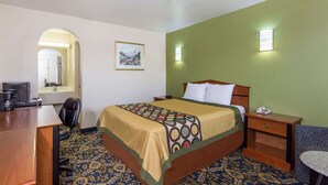 Una habitación de hotel con cama, escritorio, silla y una pequeña mesa.