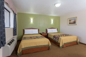 Habitación de hotel con dos camas, una ventana con cortinas, un calentador de pared y un cuadro en la pared.