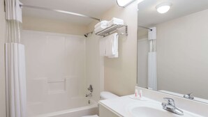 Un baño con bañera, inodoro, lavabo y un perchero con toallas dobladas.
