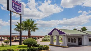 Señal de Knights Inn & Suites, entrada cubierta y estacionamiento con palmeras.