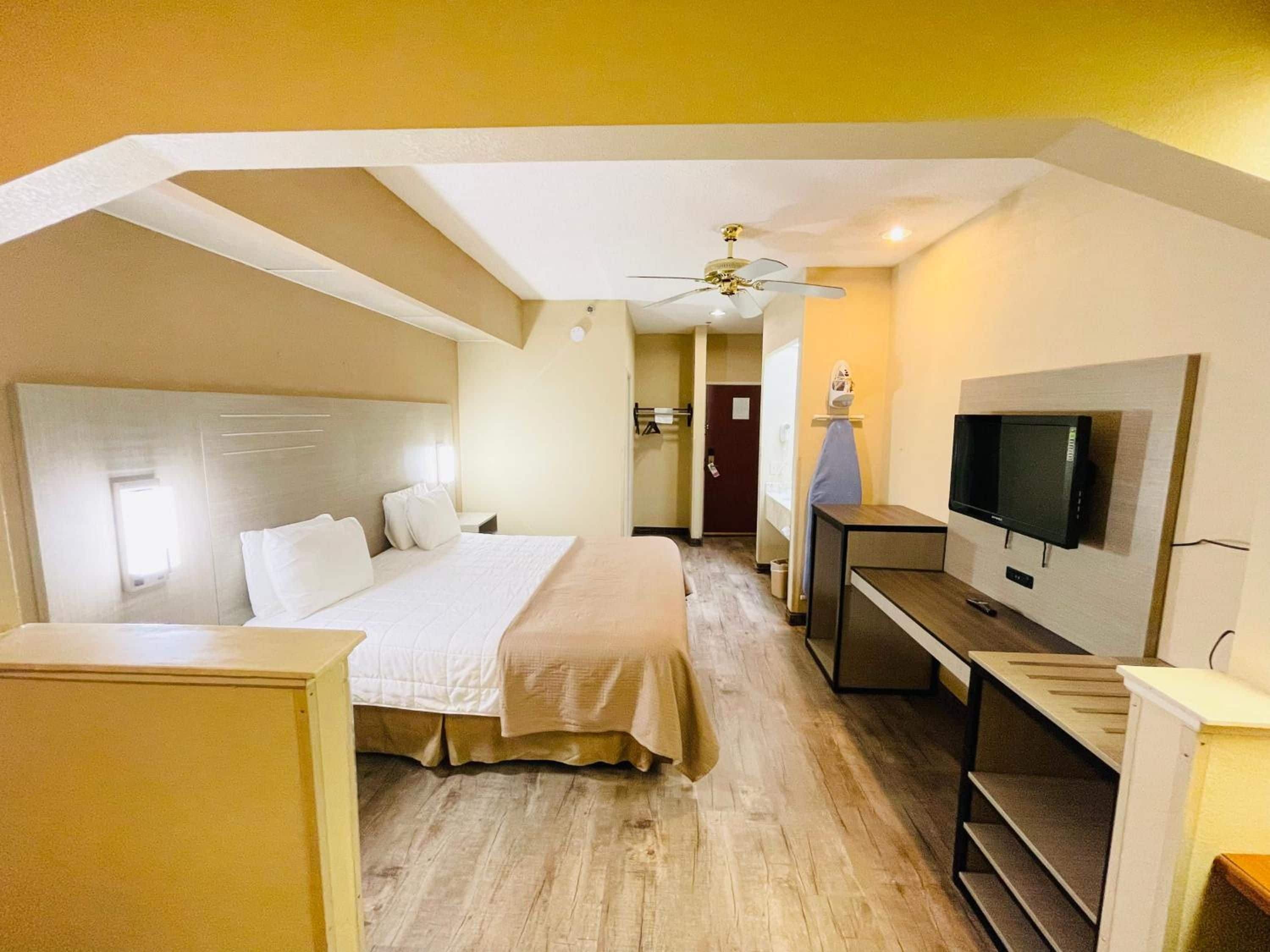 Ein Hotelzimmer mit einem Bett, einem Fernseher, einem Schreibtisch und einem Deckenventilator.