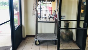 A hotel entrance with a metal cart, a 'Push' sign, and a view of the outside. - America's Best Inn and Suites Flowood (Flowood)