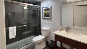 A bathroom with a glass-enclosed shower, a toilet, a sink with a mirror, and a framed picture on the wall. - Motel 6 San Francisco, CA - Fisherman's Wharf (San Francisco)