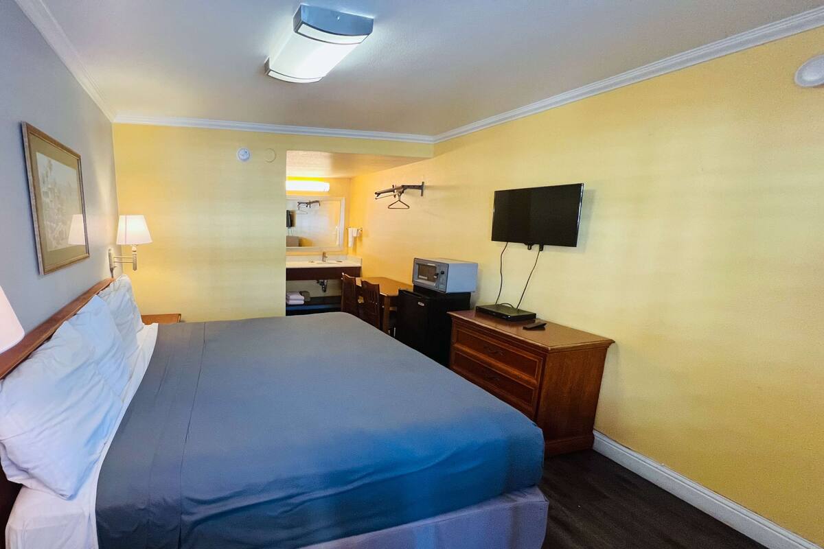 A hotel room with a bed, a desk with a computer, a TV, and a mirror.