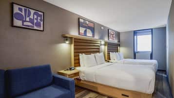 Une chambre d’hôtel avec un lit, deux tables de chevet, une chaise et des œuvres d’art accrochées aux murs.