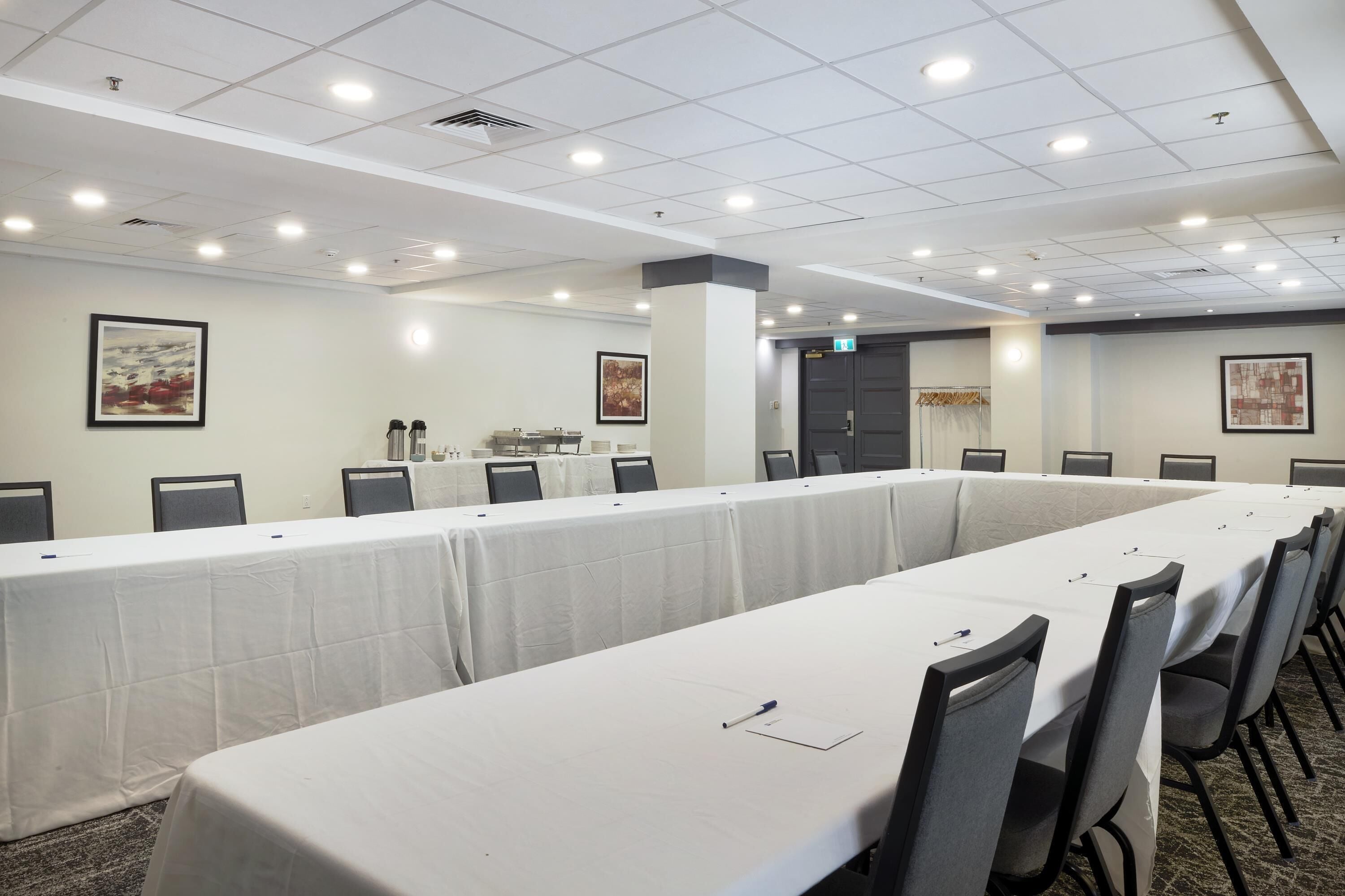 A conference room with long tables, chairs, and ceiling lights.