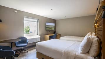 A hotel room with two beds, a desk, a chair, a TV, and a window with a view.