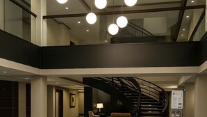 Un hall amplio con un sofá seccional grande, una escalera y una moderna lámpara de araña.