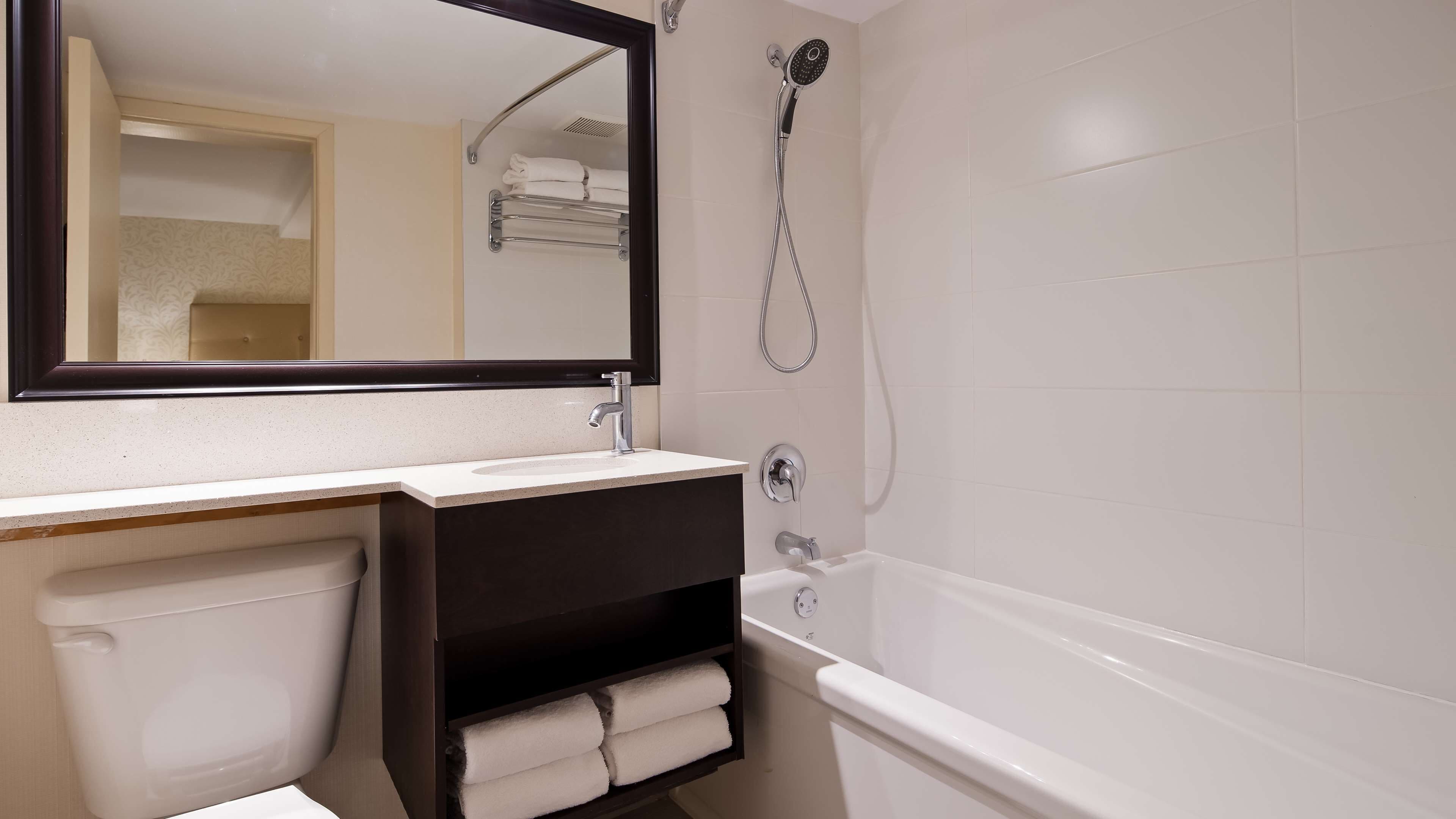 Une salle de bain avec un lavabo blanc, un meuble-lavabo foncé, des toilettes blanches et une baignoire blanche.