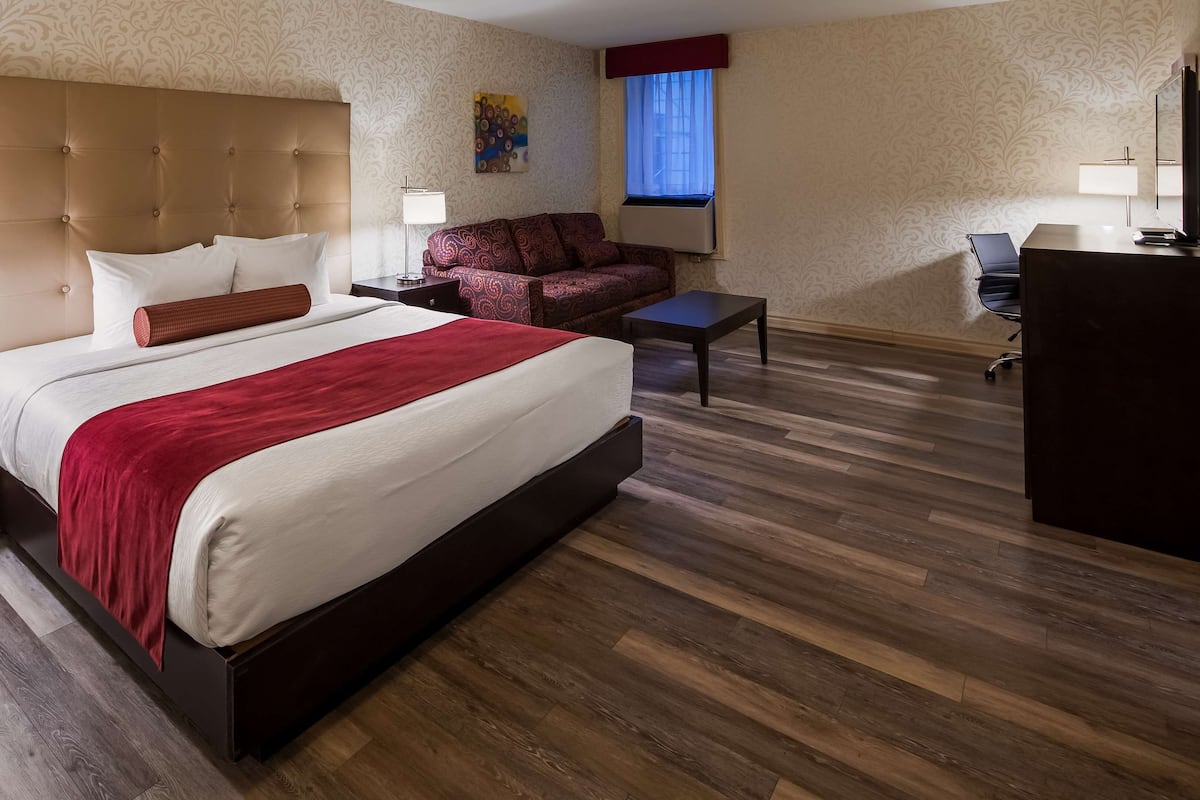 Una habitación de hotel con una cama grande, un sofá, un escritorio y un televisor.