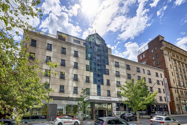 Un hotel amb una façana moderna, un entrada destacada i una vista clara del cel.