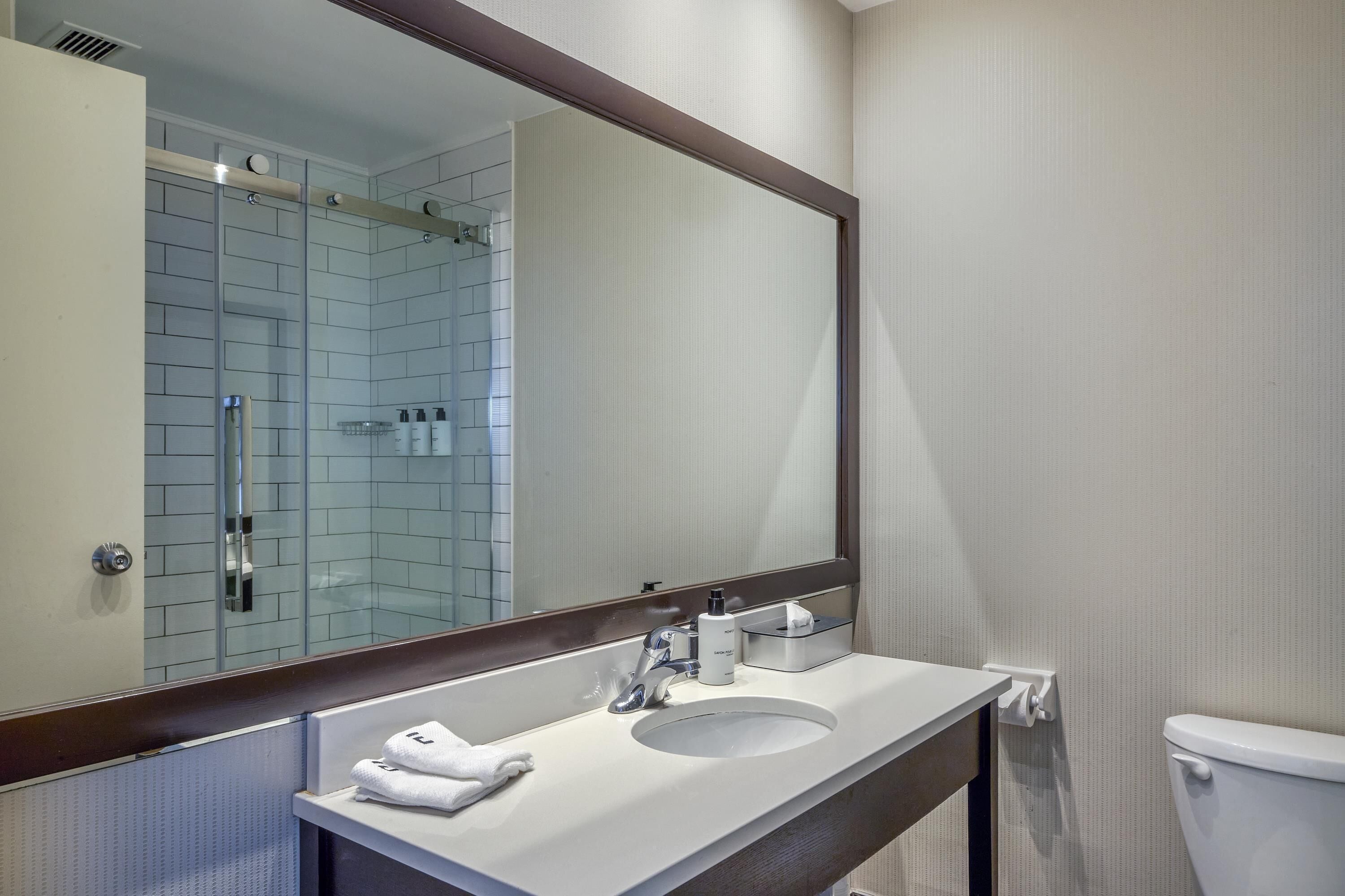 Une salle de bain avec un lavabo blanc, un miroir et des toilettes.
