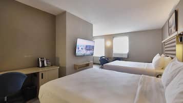 A hotel room with two beds, a desk with a coffee maker, a TV on the wall, and a chair.