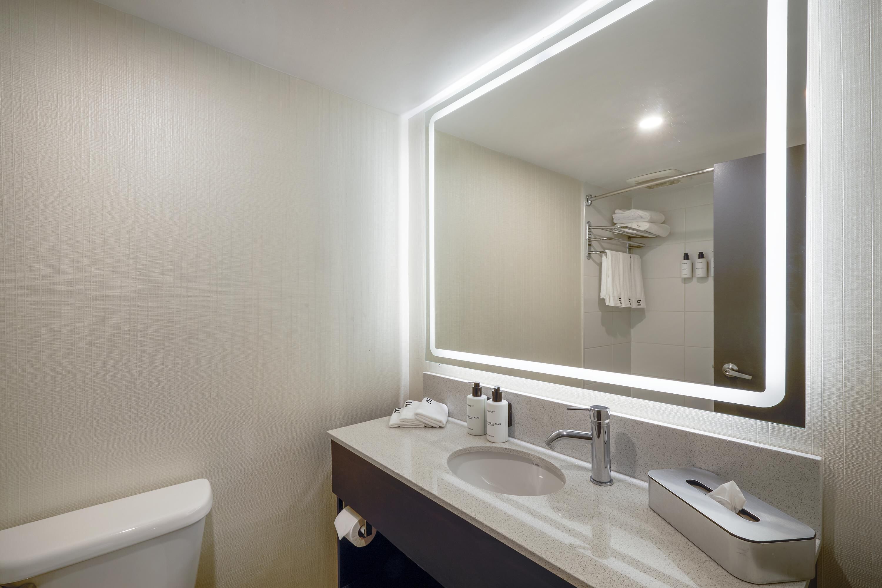 Un baño moderno con inodoro, lavamanos y espejo.