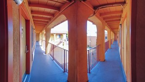 A corridor with a blue floor, red walls, and a series of arches supported by columns. - Inn at Golden Gate (San Francisco)