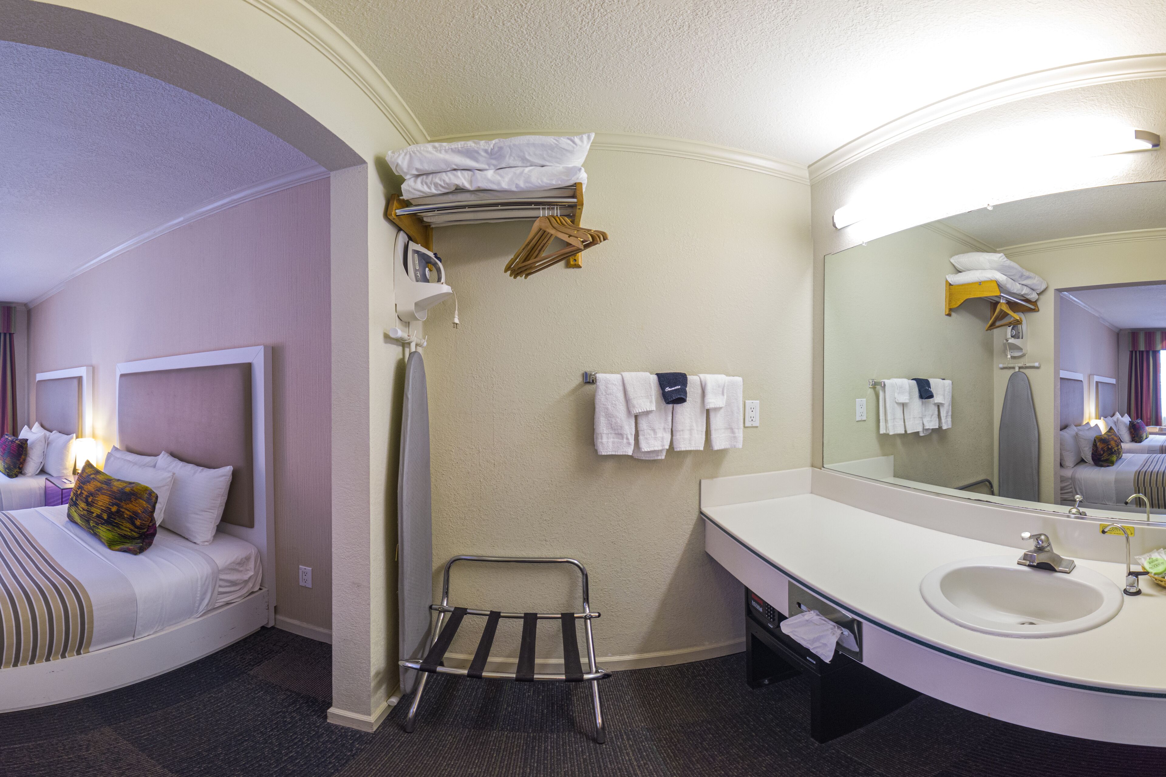 Une chambre d’hôtel comprenant un lit, une salle de bain avec un lavabo et un miroir, et un porte-serviettes.