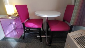 A small hotel room with a single round table and two chairs, a desk with a lamp, and a radiator. - Inn at Golden Gate (San Francisco)
