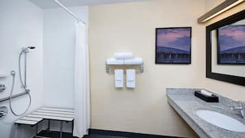 A modern bathroom with a shower, a sink, and a towel rack.