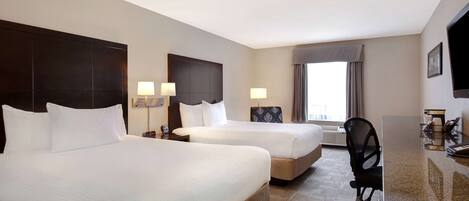 Quarto de hotel com duas camas, uma escrivaninha, uma cadeira e uma televisão.