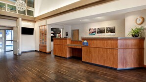 A hotel reception area with a wooden reception desk, a clock, and framed pictures on the wall.