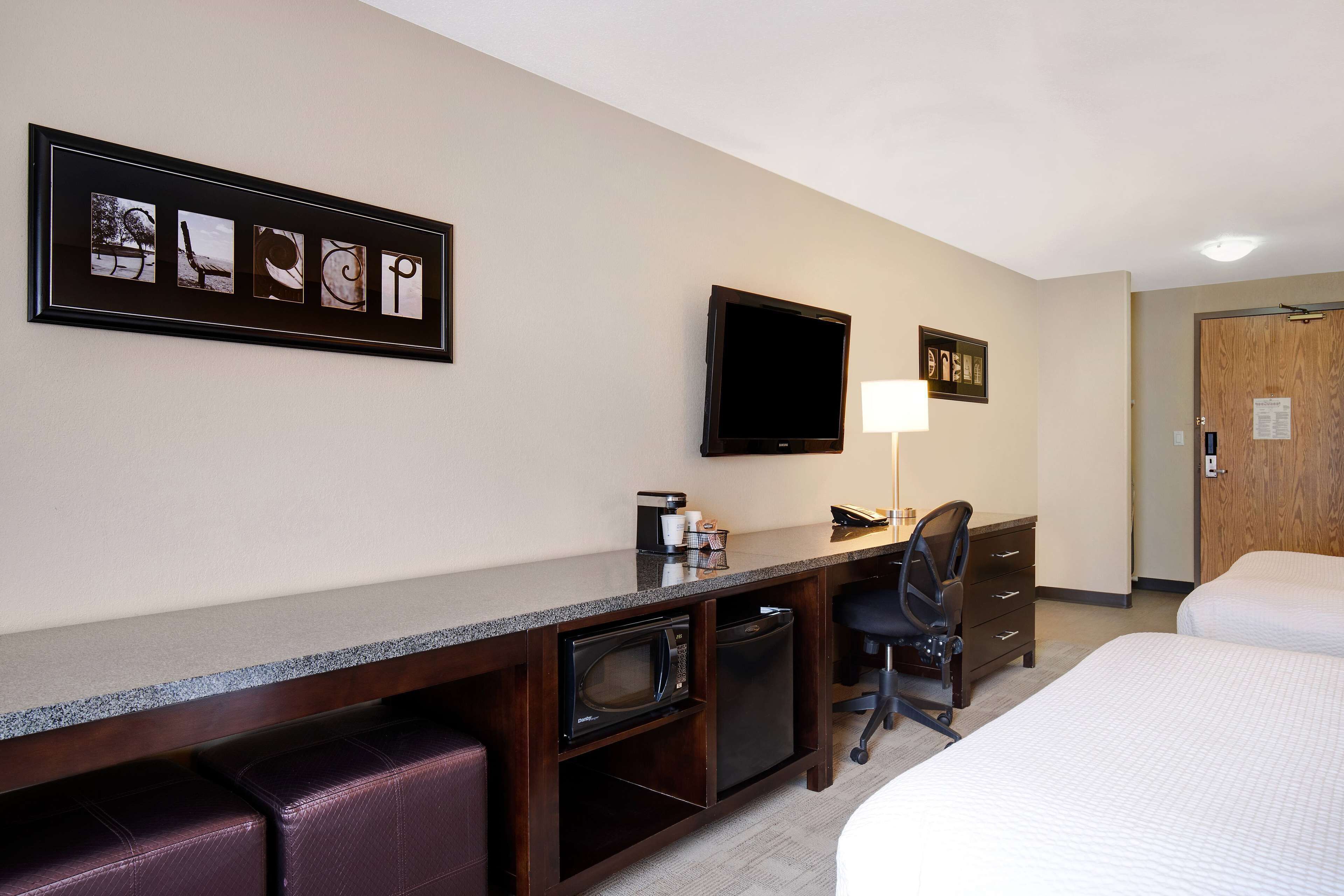 A hotel room with a bed, a desk with a computer, a TV, and a microwave.