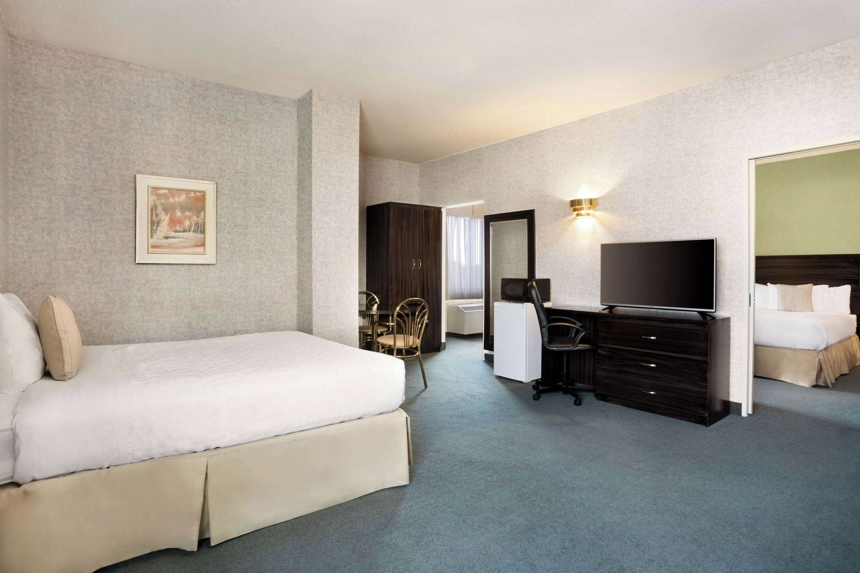 Ein Hotelzimmer mit Bett, Schreibtisch, Fernseher und Spiegel.