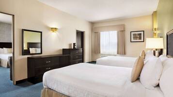 A hotel room with two beds, a dresser, a mirror, and a window with curtains.