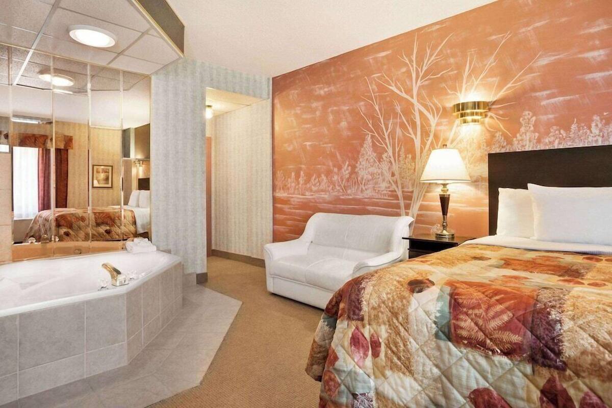 Ein Hotelzimmer mit einem großen Bett, einer separaten Sitzecke, einer Badewanne und einer Wandleuchte.