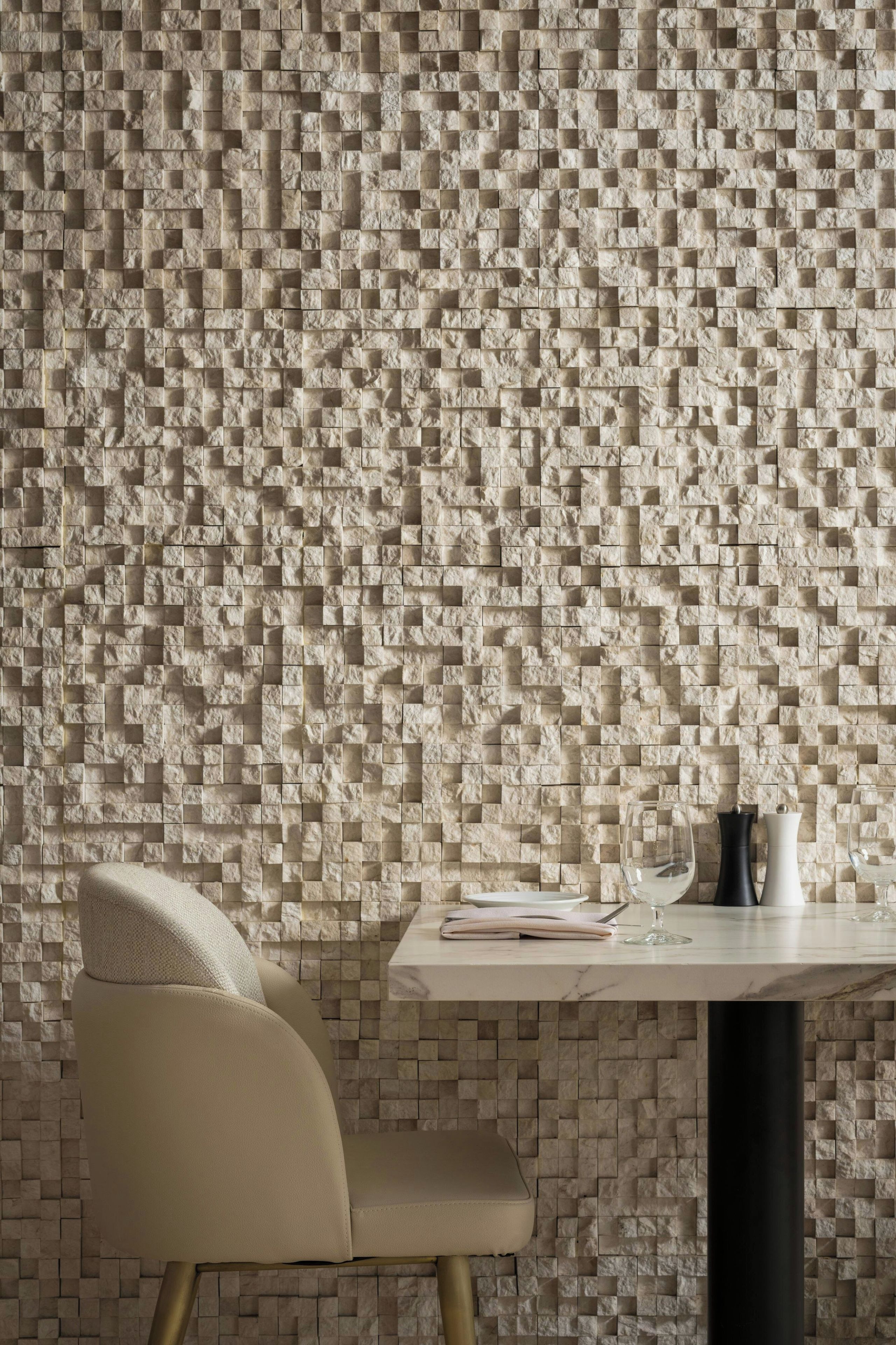 A modern interior with a textured wall, a dining table, and a chair.