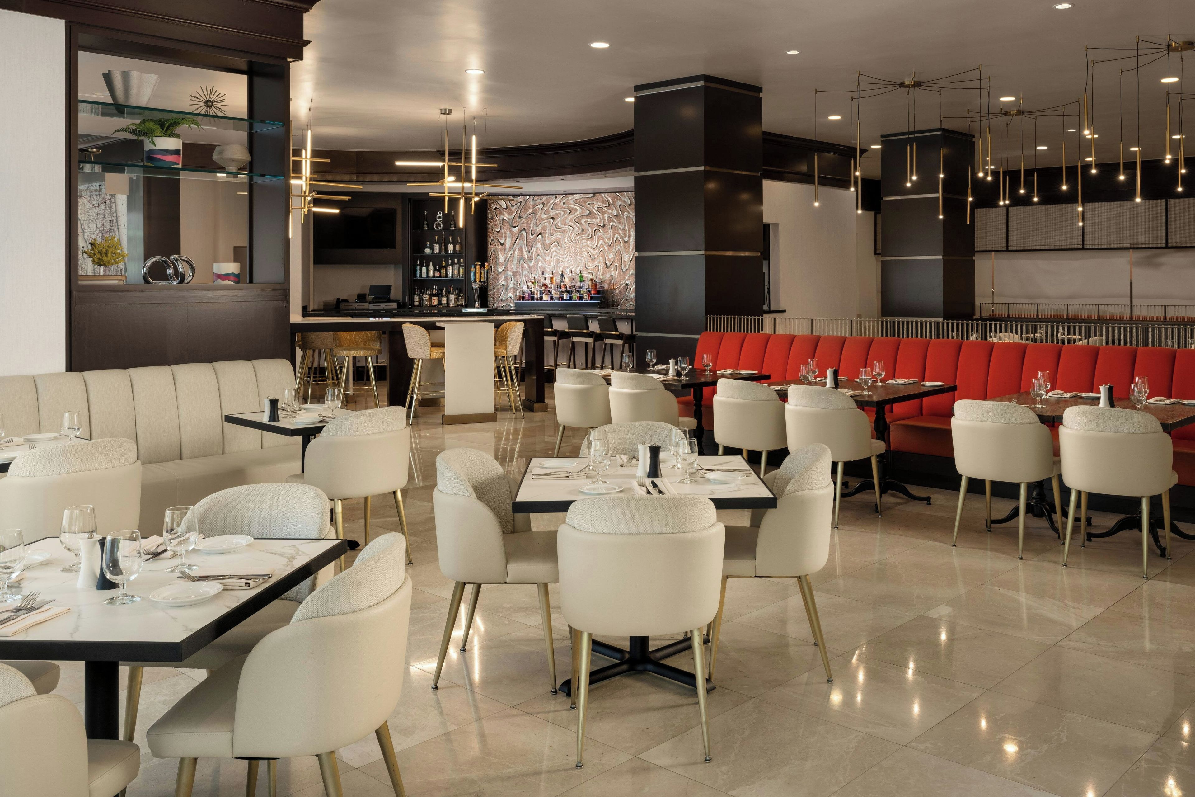 Un interior de restaurante moderno con varias zonas de comedor, incluyendo un bar y una sección con cabinas.