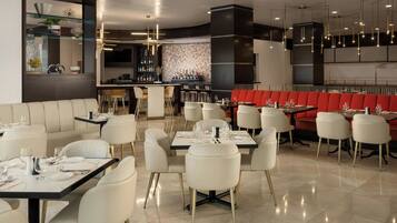 Un interior de restaurante moderno con varias zonas de comedor, incluyendo un bar y una sección con cabinas.